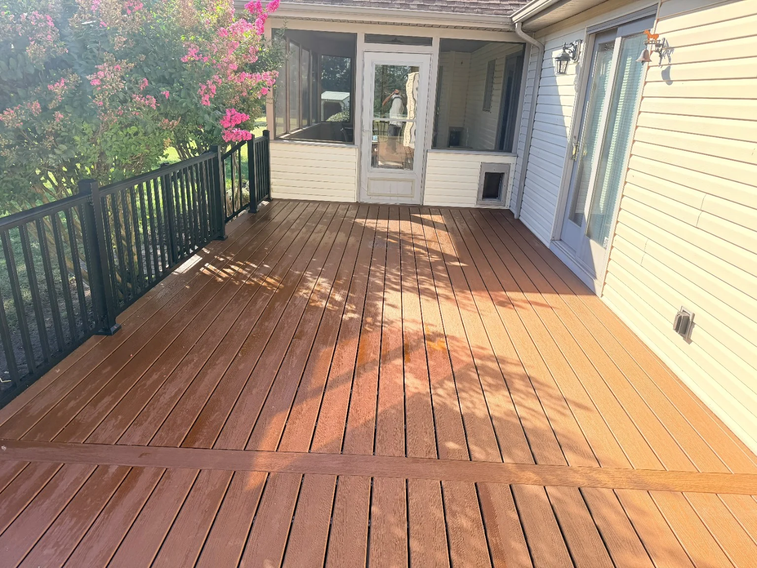 After: installed deck boards beside the screened porch and black railing