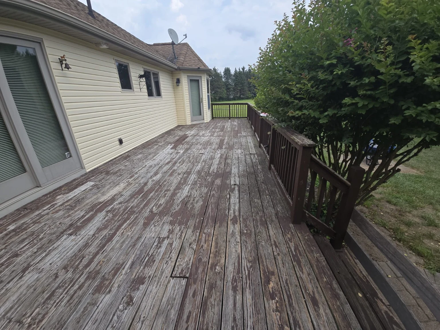 Before: weathered wooden deck boards and old brown railings along the house