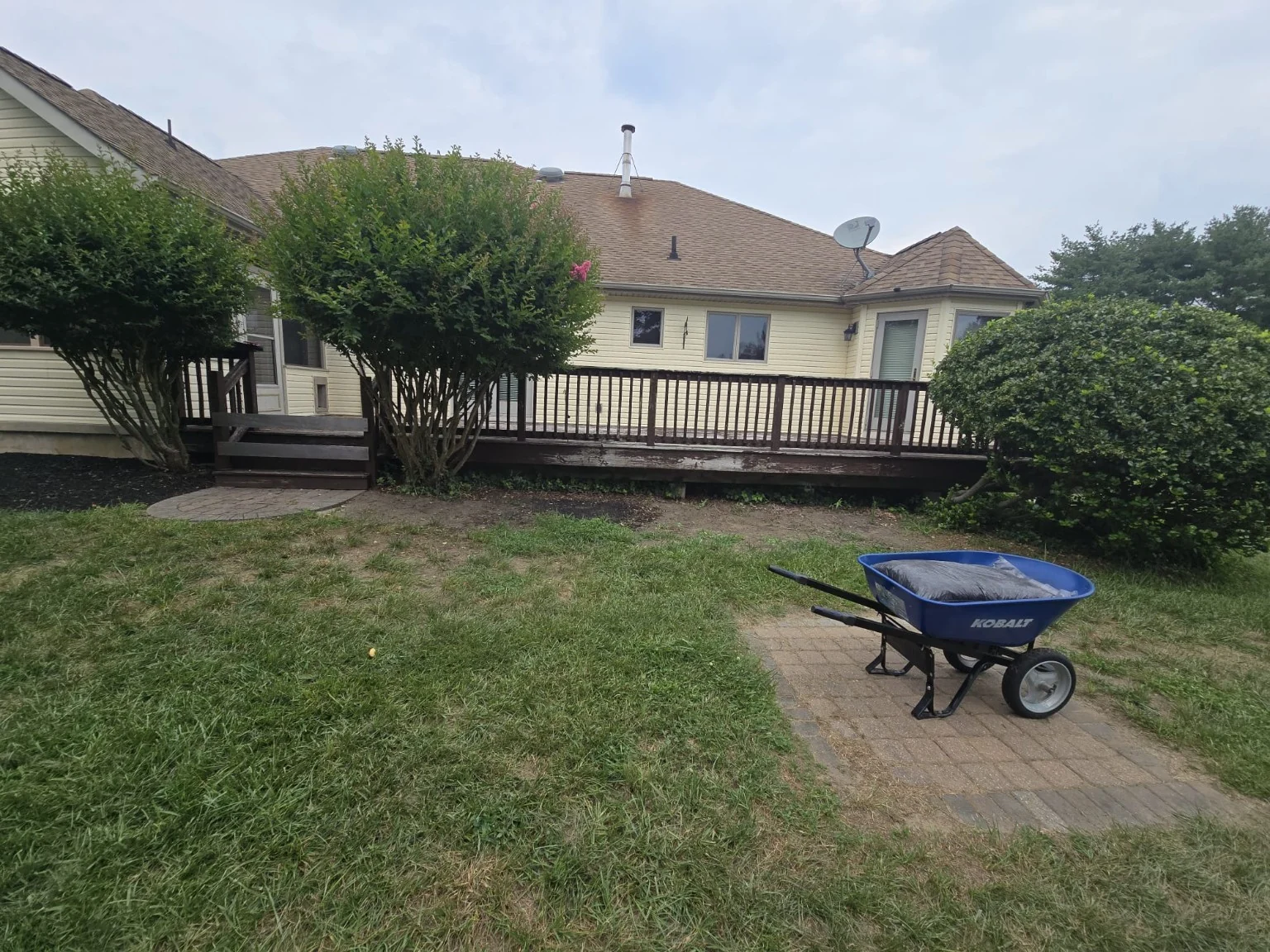Before: original wooden deck, worn fascia and brown railings, front view