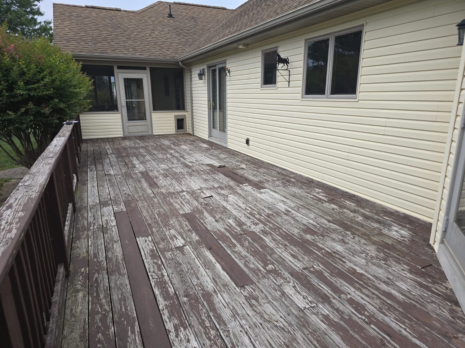 Before: worn wooden deck surface looking back toward the screened porch