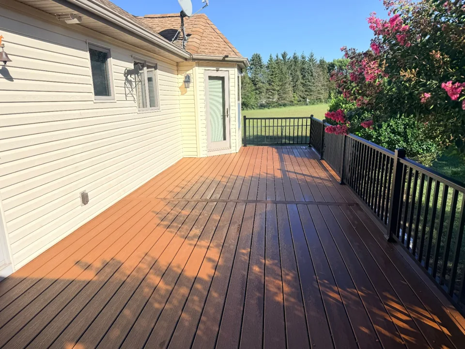After: completed deck surface and black railing beside the house