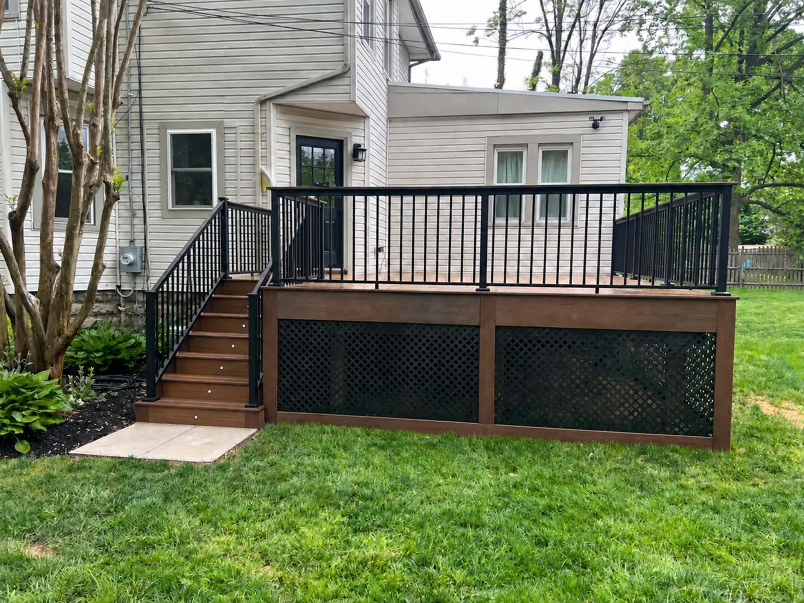 Deck with dark railing, stairs and a lattice enclosure — Zenna Decks portfolio