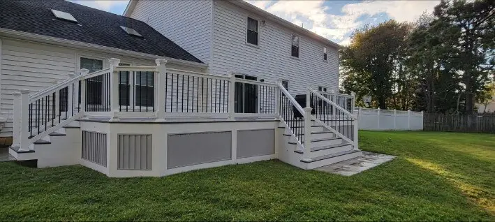 Zenna Decks deck with white railings, dark balusters and stairs leading to the lawn